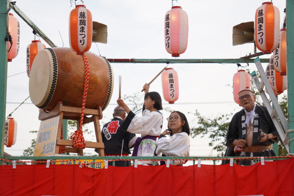 櫓上で太鼓をたたく人や鈴を鳴らす人達