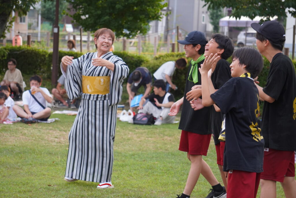 盆踊りを楽しそうにする中学生と老人