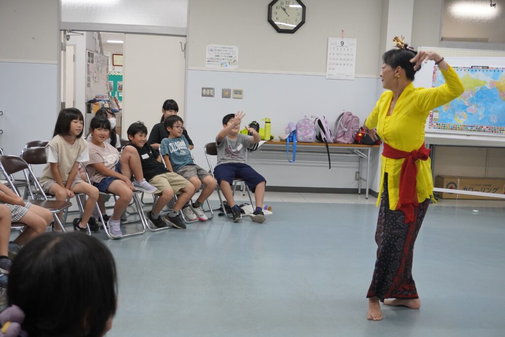 バリ舞踊を踊る先生と、それを見ている小学生たち