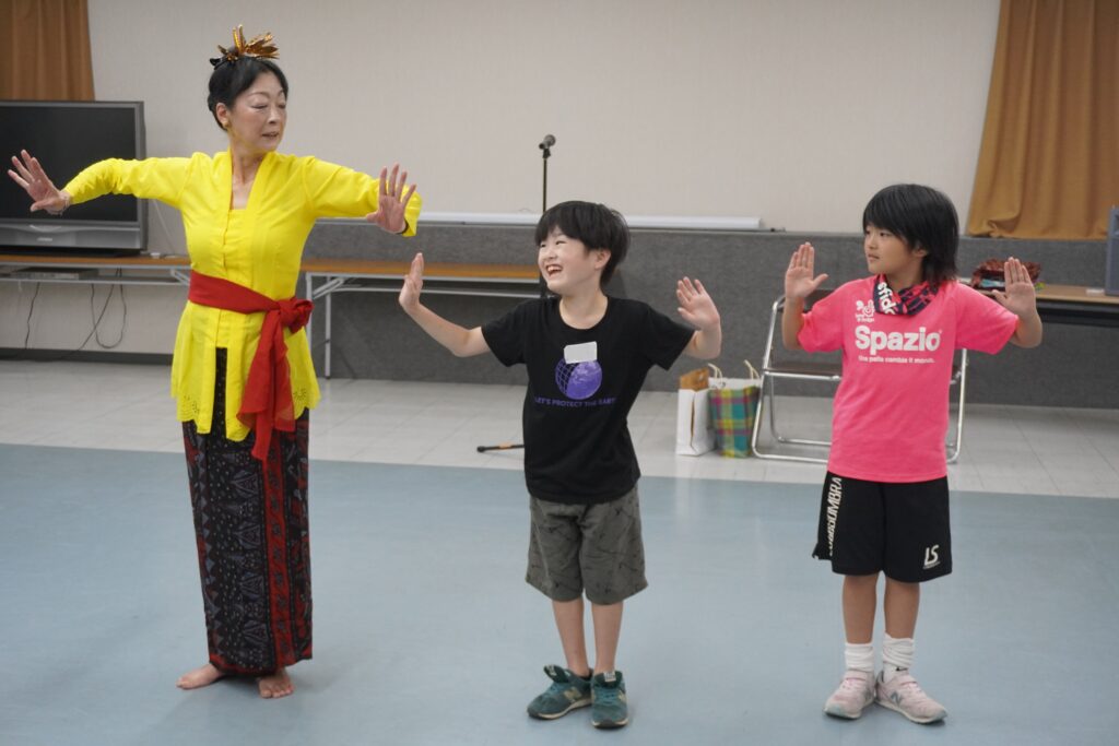 バリ舞踊を踊る先生と、一緒に踊っている小学生たち