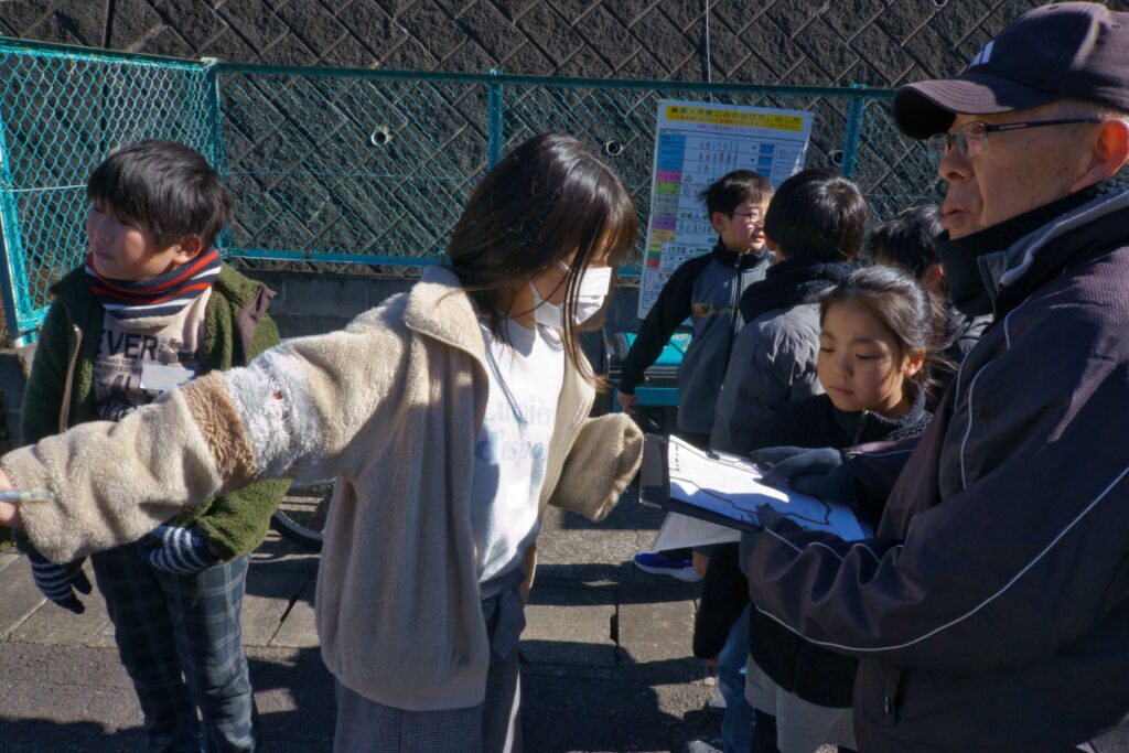 外で地図を確認している生徒たちとサポーター