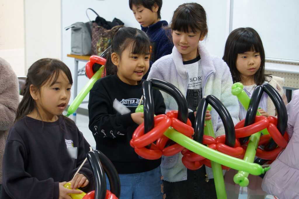 バルーンの弓で矢を飛ばす子どもたち