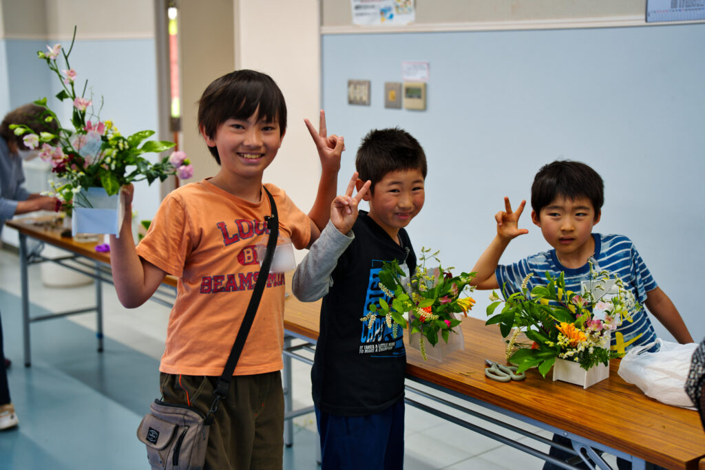 活けた花と共に記念撮影をする子どもたち