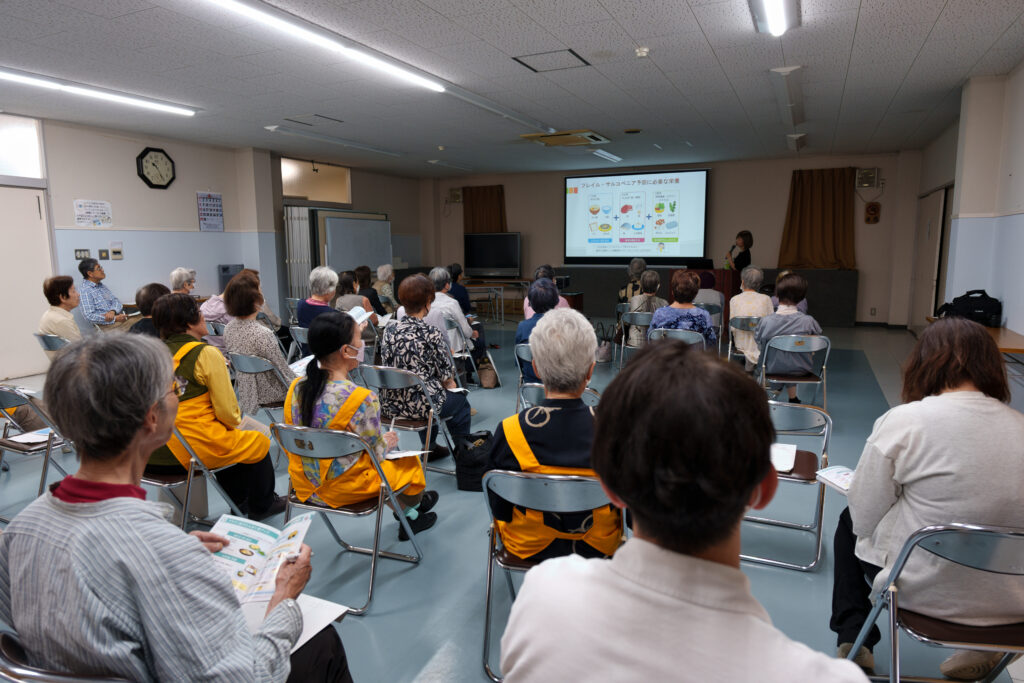 スクリーンを見て説明を聞く会員たち