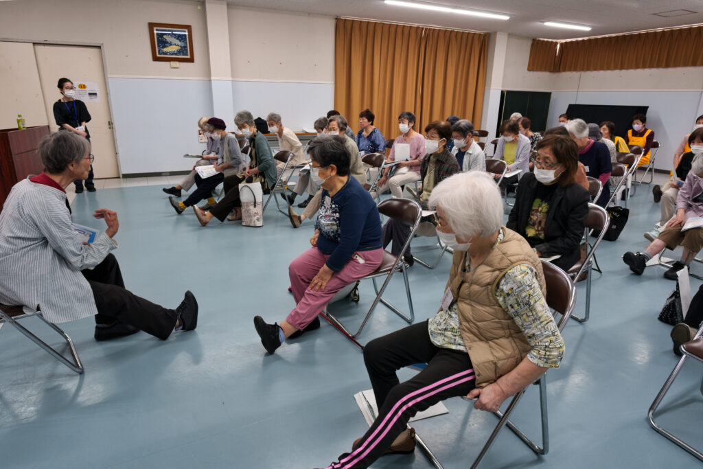足を伸ばす体操をする落合先生と会員たち