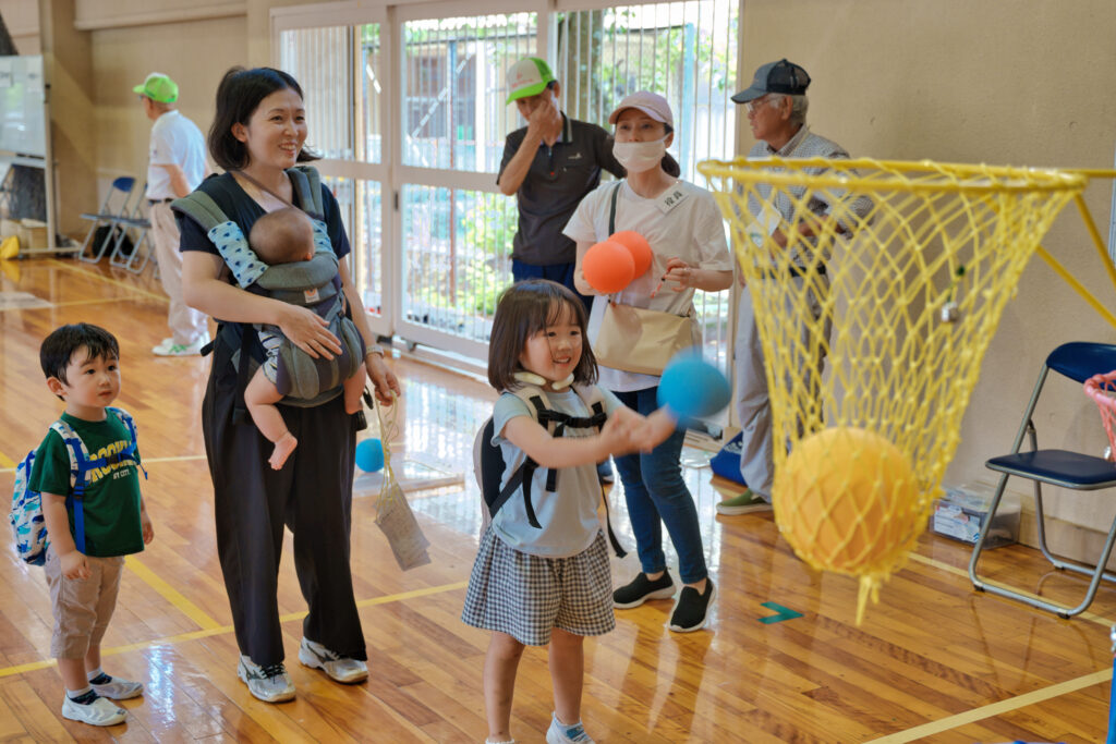 ボールを投げる子どもと、それを見守る人たち
