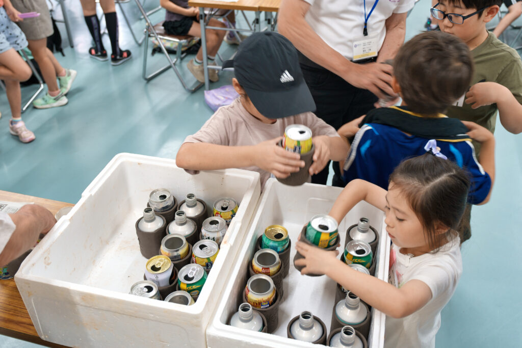 完成したマグカップを発泡スチロールに入れる子どもたち