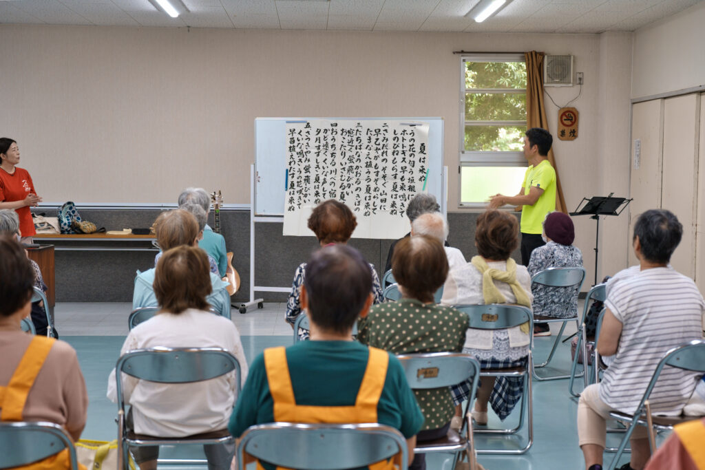 講師の手拍子に合わせ歌う会員たち