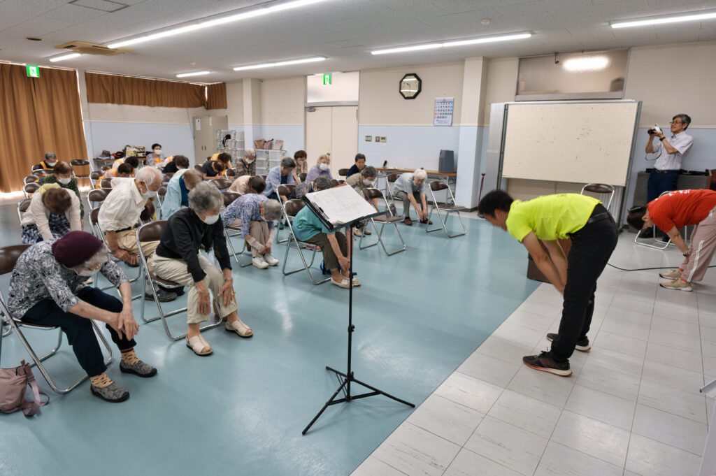 前屈みで足先を触る講師と会員たち