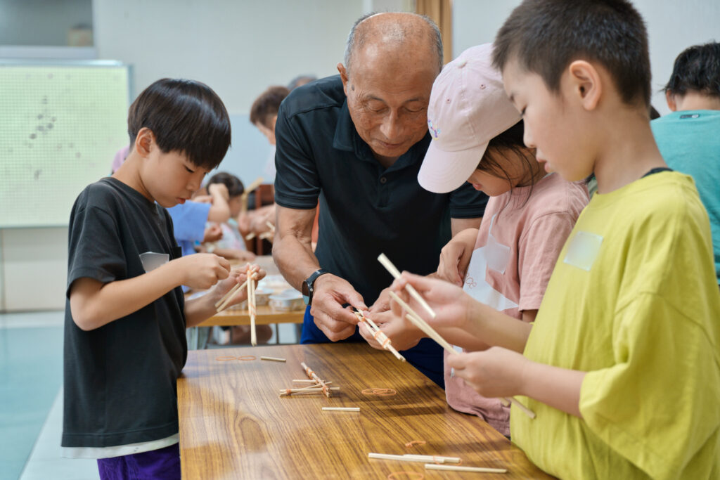 サポータに割り箸鉄砲の作り方を教わる子どもたち