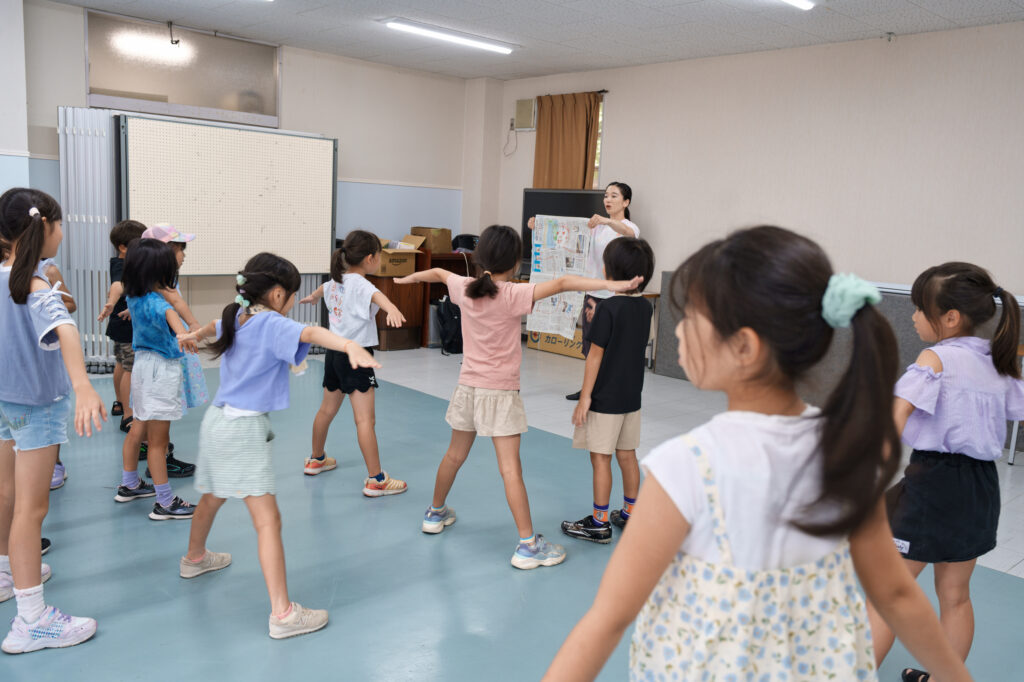 新聞紙に合わせて手を広げる子どもたち