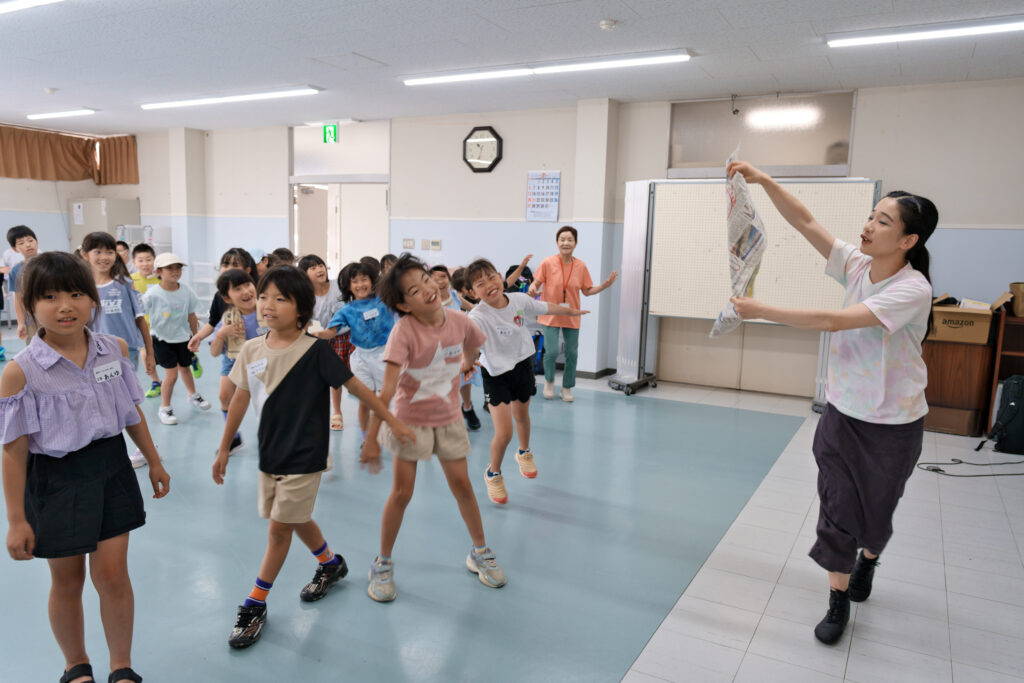 新聞紙を持ったまま動く宮城先生と、それに合わせて動く子どもたち