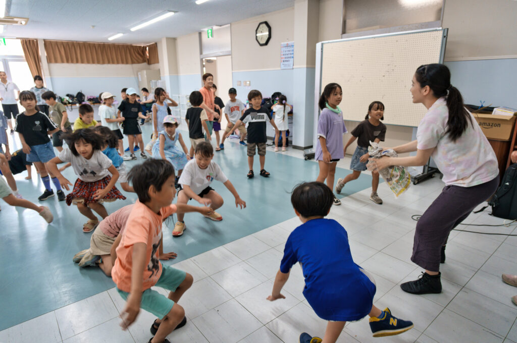 新聞紙をぐしゃぐしゃにする宮城先生と、それを表現しようとする子どもたち