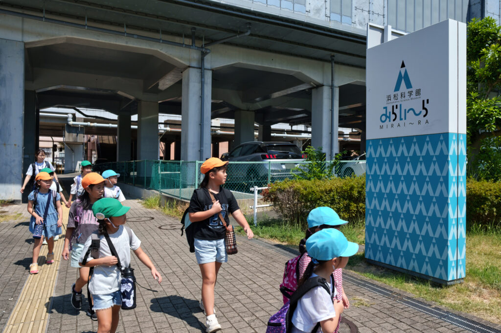 みらいーらの看板の前を通る子どもたち