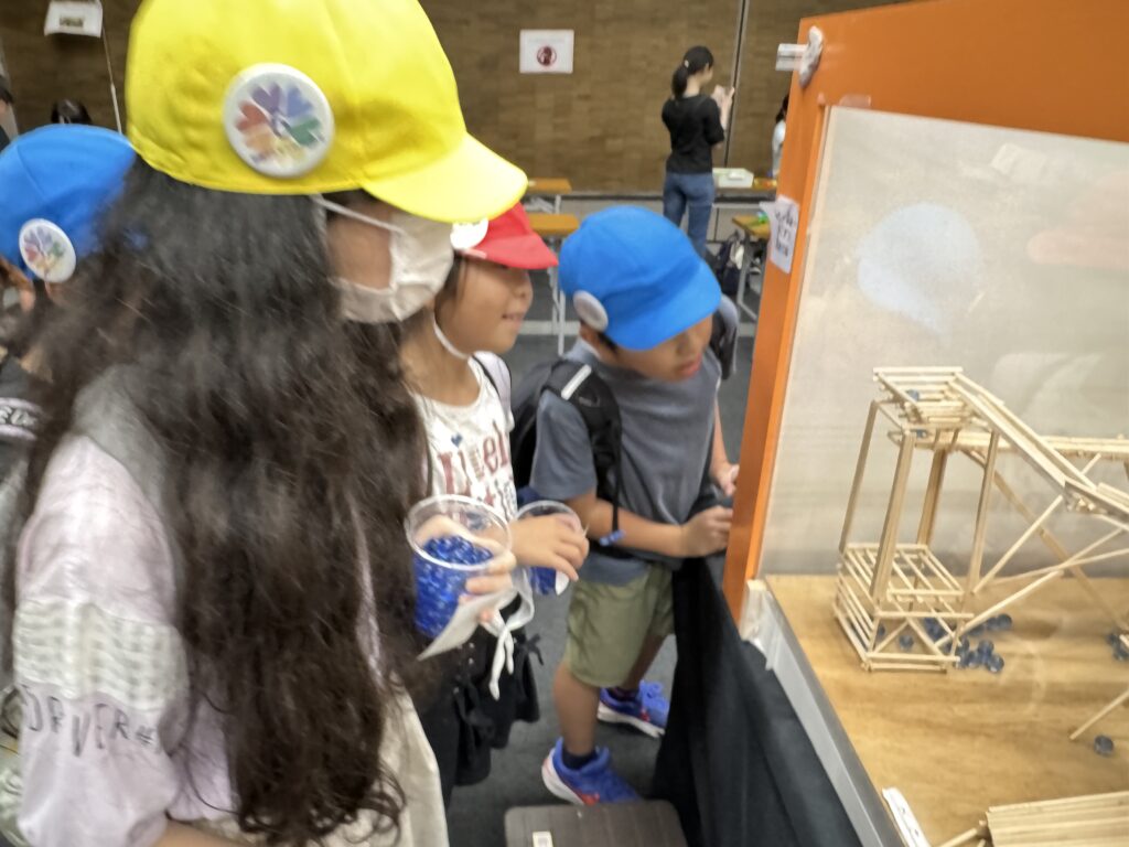 割りばしで作られた装置で遊ぶ子どもたち