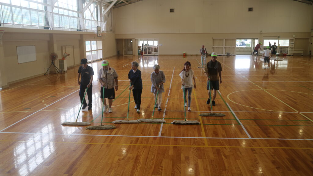 体育館にモップを掛ける役員たちと、参加者たち