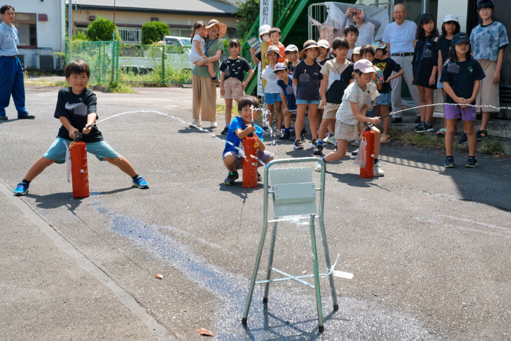 水消火器を的へ向け、放水する子どもたち