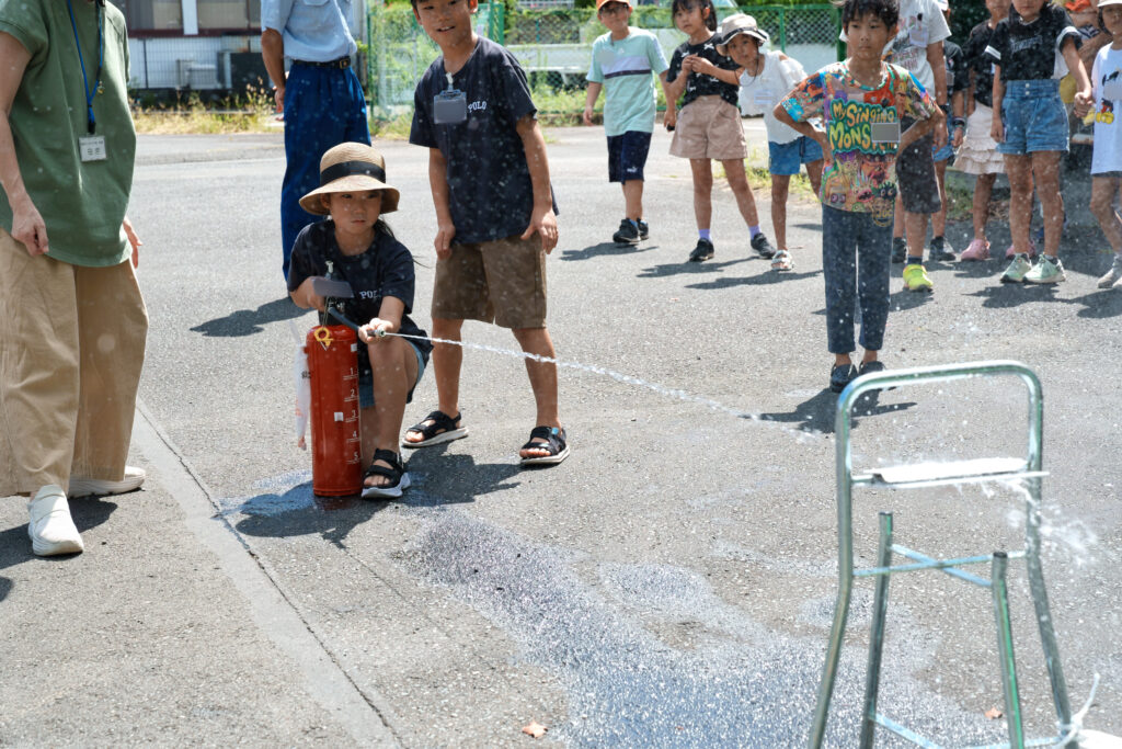 水消火器を的へ向け、放水する子ども