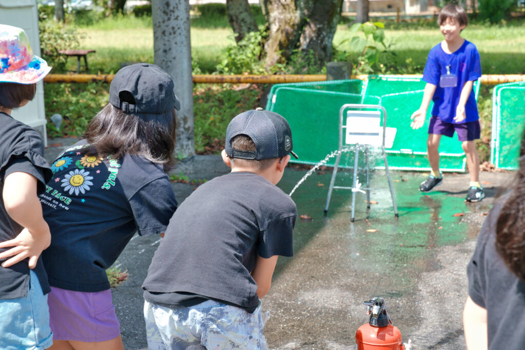 水消火器を的へ向け、放水する子どもたち