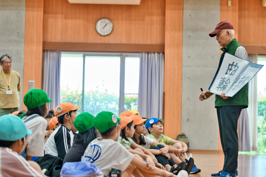 松澤先生が紙を使って解説し、それを聞く子どもたち