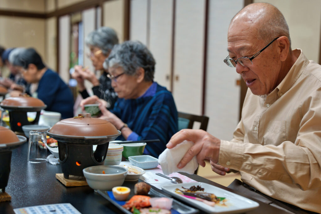 料理を食べている自治会長