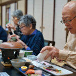 料理を食べている自治会長