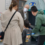 防災テントの解説をする防災委員と、解説を受ける親子