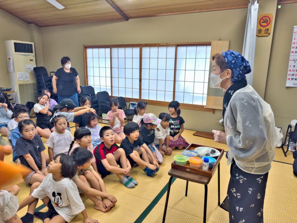 おはぎの作り方を説明する先生と、聞く子どもたち