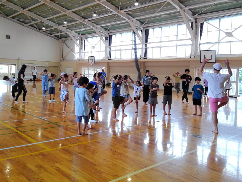 講師の声に合わせて「雑草」のポーズをとる子どもたち