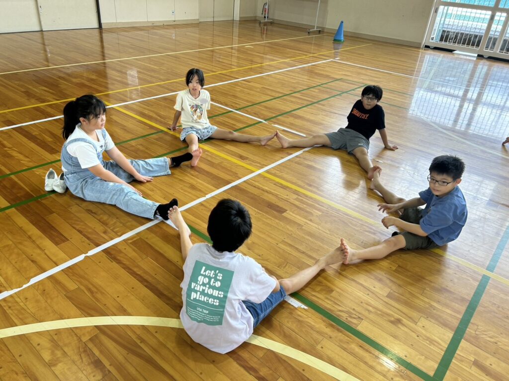 5人グループの皆で協力し、足で星を作っている子どもたち