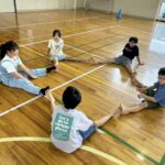 5人グループの皆で協力し、足で星を作っている子どもたち