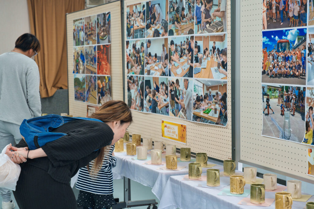 子ども教室で作成したカップや写真を見る親子