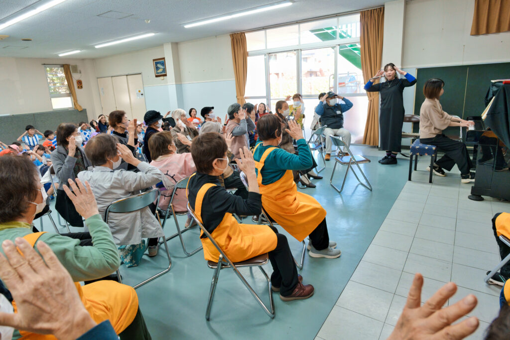 「ママフェリス」の演奏で歌を歌う幼稚園児と会員たち