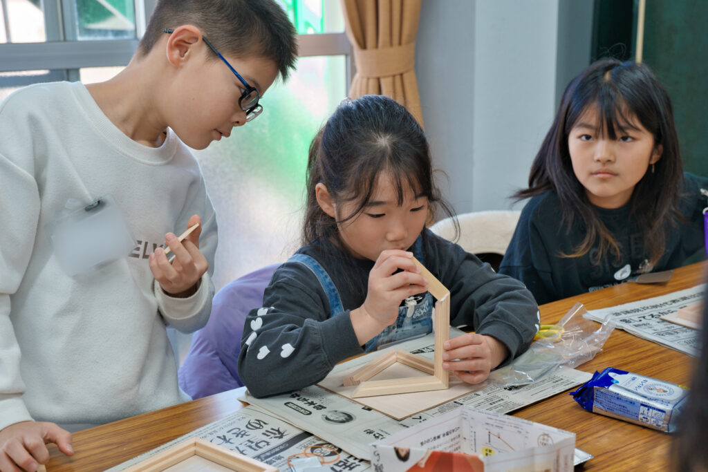 ボンドを桧の枠に付け、くっつけている子どもたち