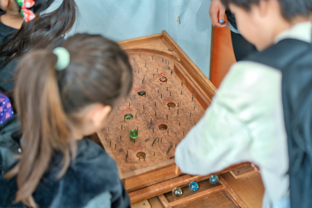 ビー玉と木でできたゲームで遊ぶ子どもたち
