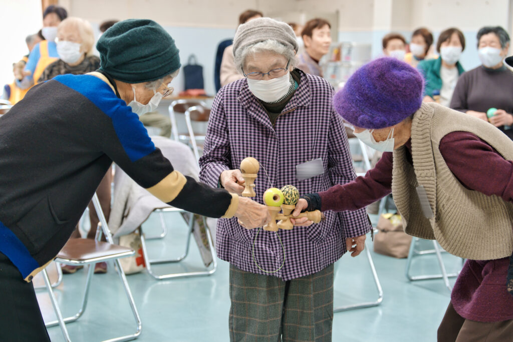 皿に球を乗せたけん玉を手に持ち、歩いて交流をする会員たち