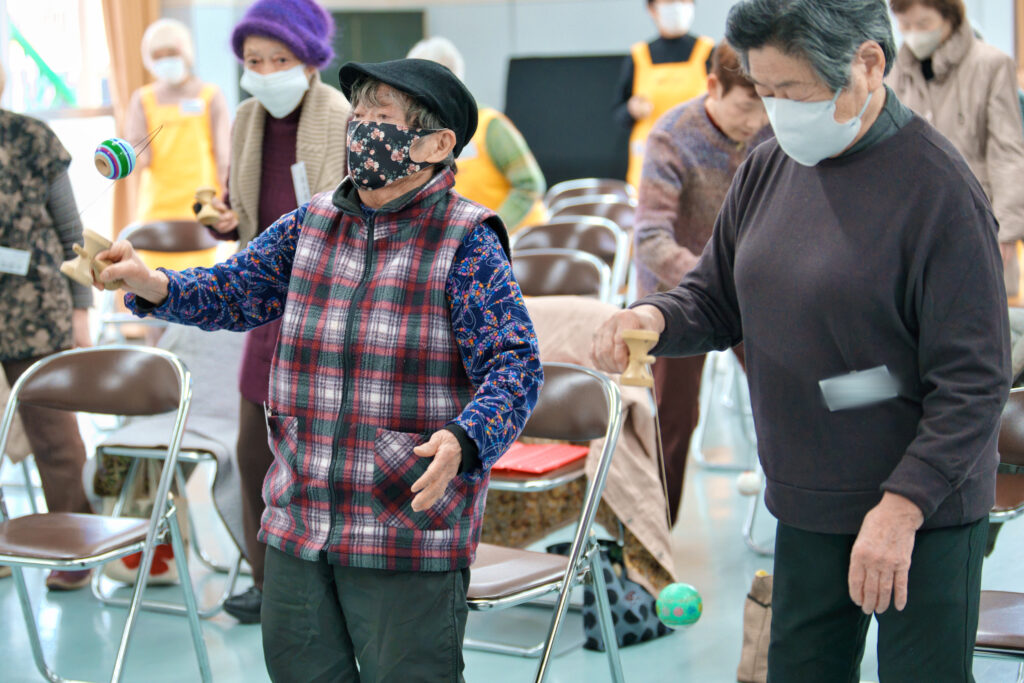 球を上にあげ、皿で受け止めようとしている会員たち