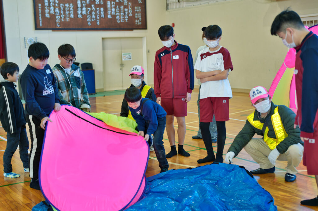 避難所用テントを組み立てる小中学生と手伝う役員たち