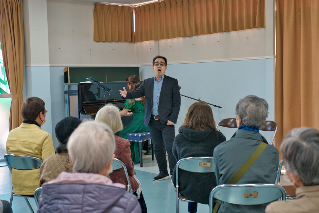 歌う八巻千尋さんと、ピアノを弾く八卷恵理さんと、音楽を聴く観客たち