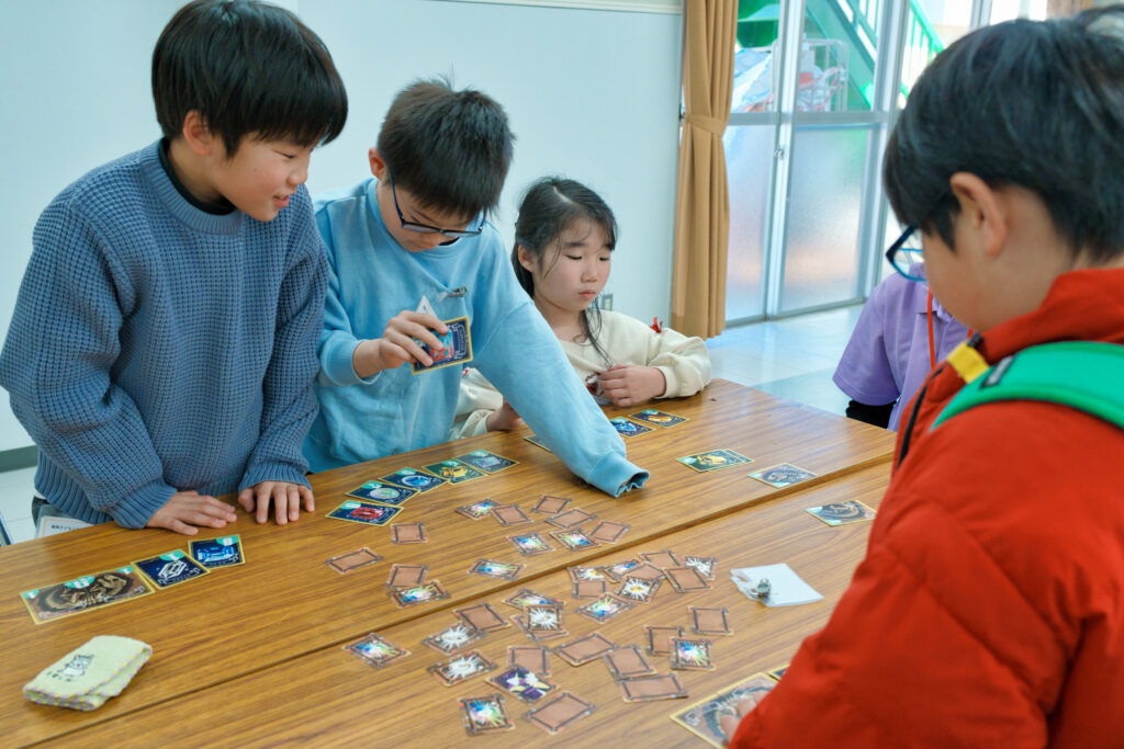 土のカードから、宝石や化石を見つけるゲームを楽しむ子どもたち