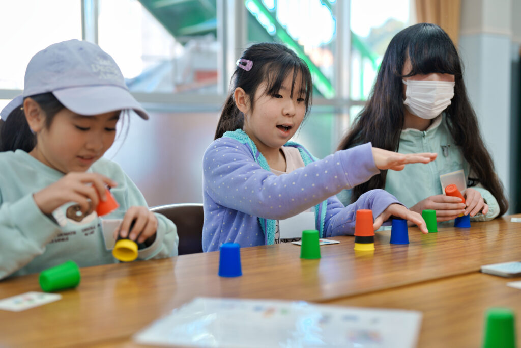 見本に沿ってカップを素早く並べるゲームを楽しく遊ぶ子どもたち