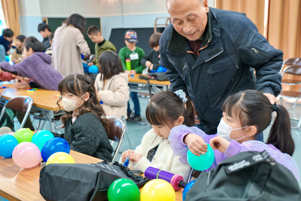 風船を膨らませる子どもたちと、見守るサポータ