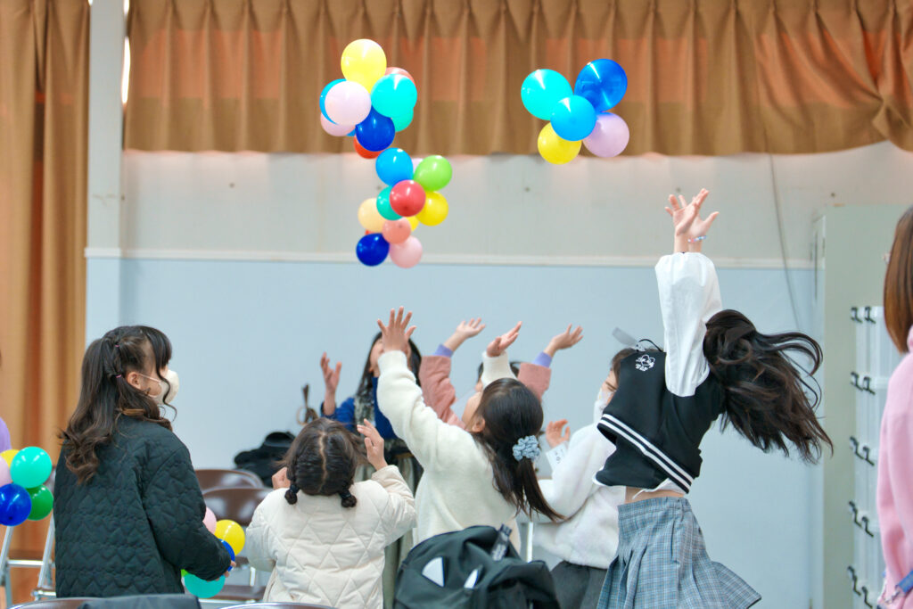 複数の繋げた風船を投げて遊ぶ子どもたち
