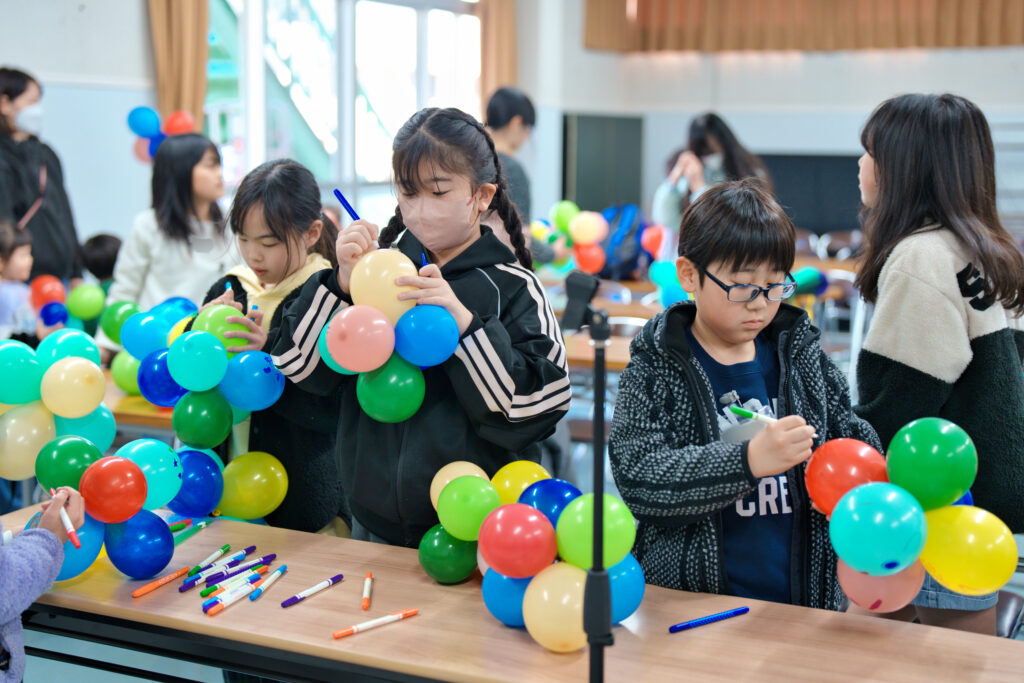 風船に文字や絵を描く子どもたち
