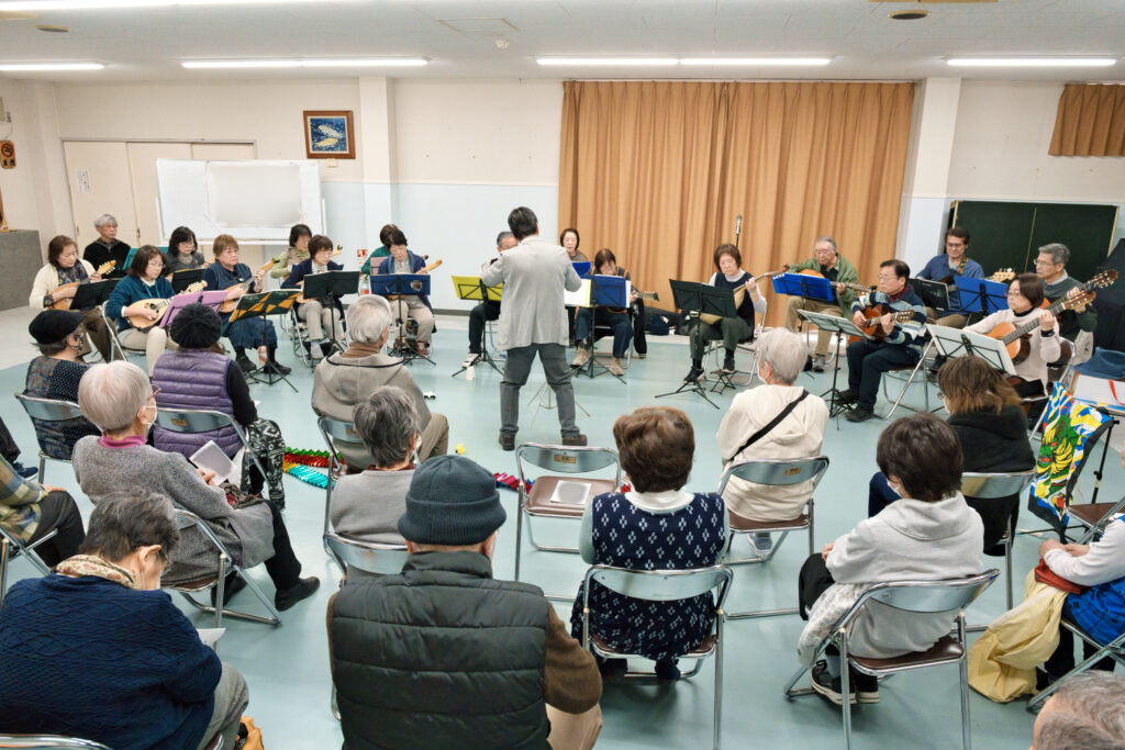 指揮に合わせ演奏するアンサンブルと、聞く会員たち