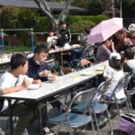 屋外のテーブルで食事をする人々