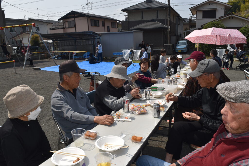 テーブルやブルーシートで交流する人々