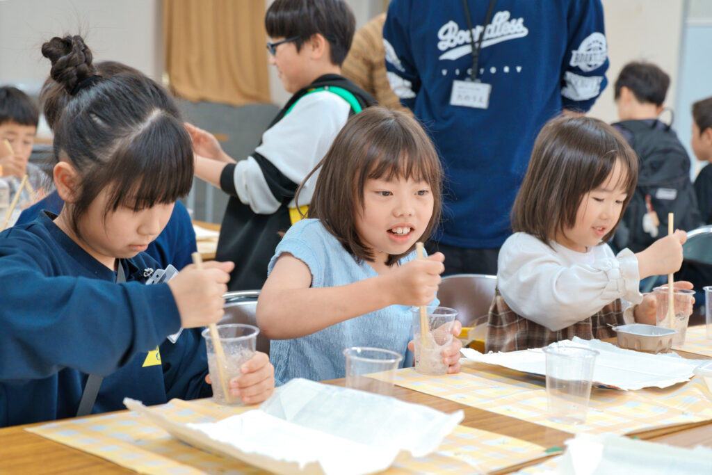 プラカップに入っを材料を割り箸で混ぜている子どもたち