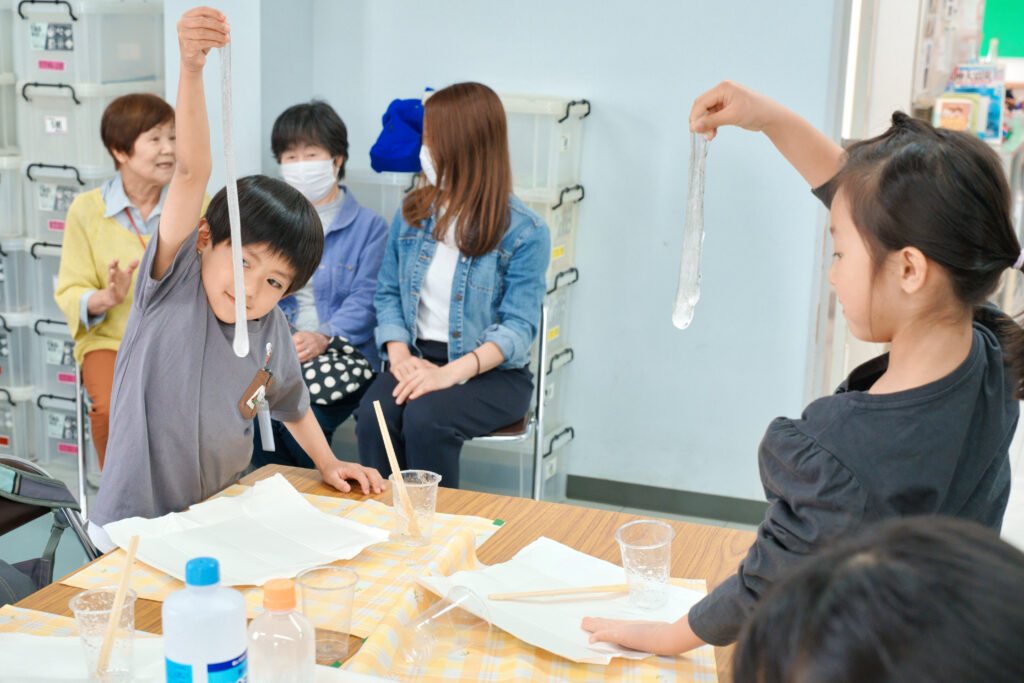 ふわふわスライムを伸ばしている子どもたち