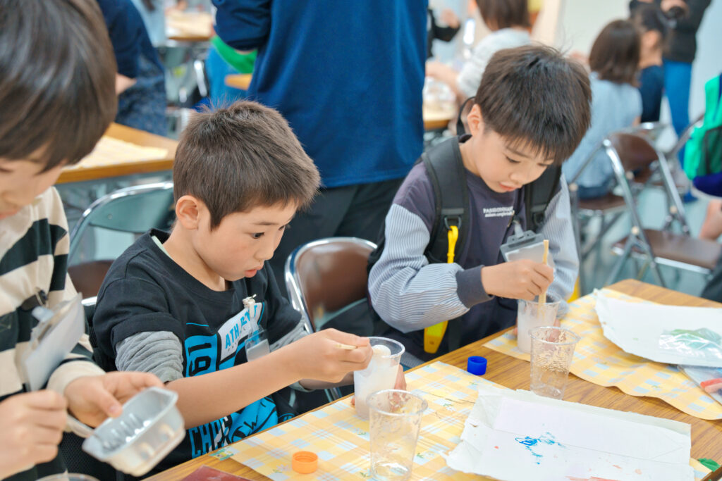 プラカップに泡を入れ、ふわふわスライムを作っている子どもたち